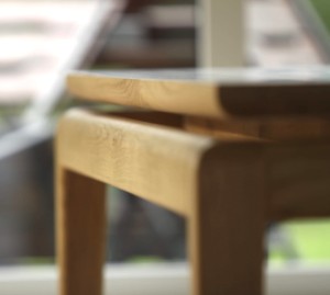Stół Enki od boku – subtelna przerwa i optycznie unoszący się blat tworzą wyjątkowy efekt lekkości. Luksusowy stół z litego dębu, zaprojektowany z dbałością o detal